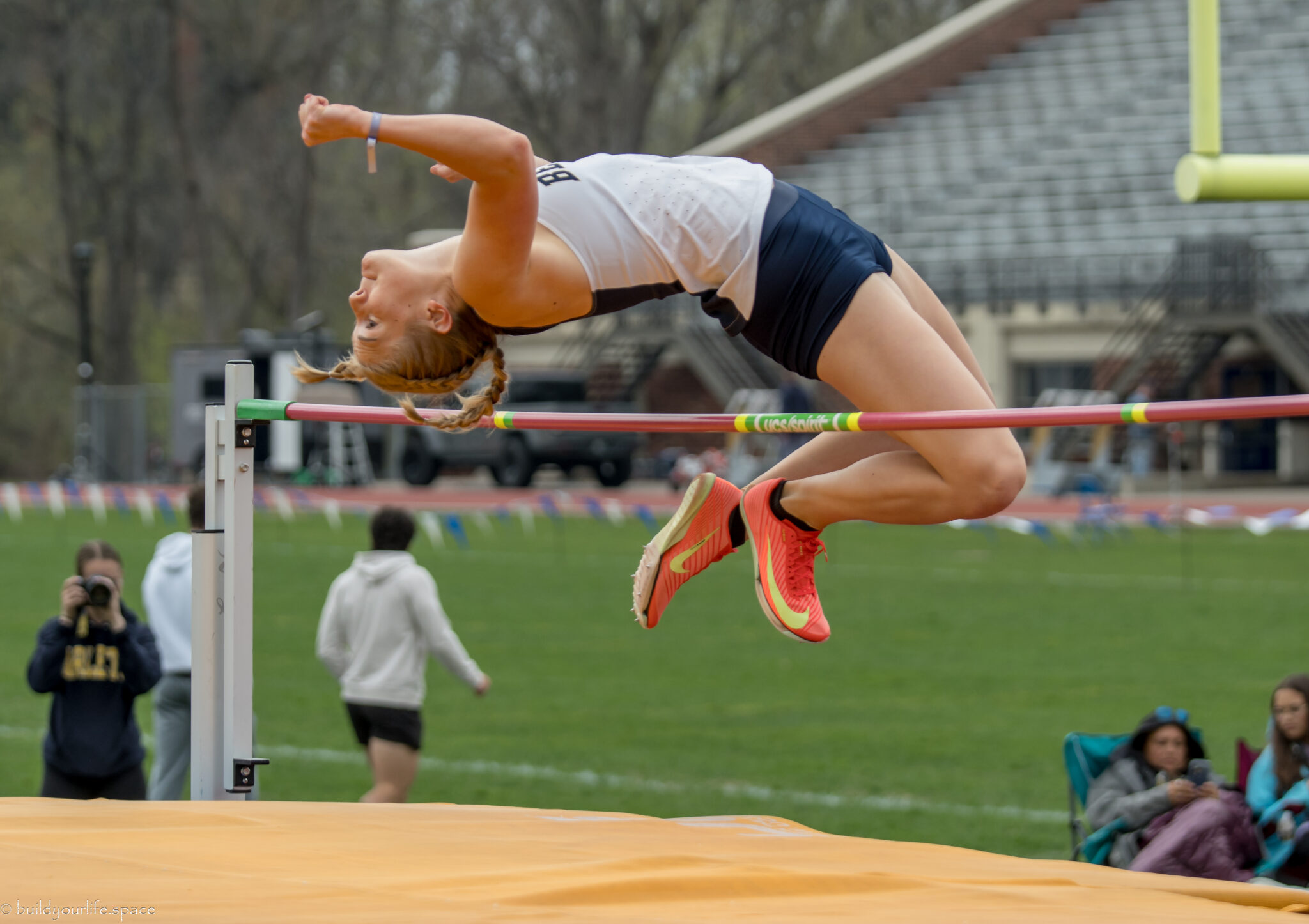 Athlete performing high jump at track meet.