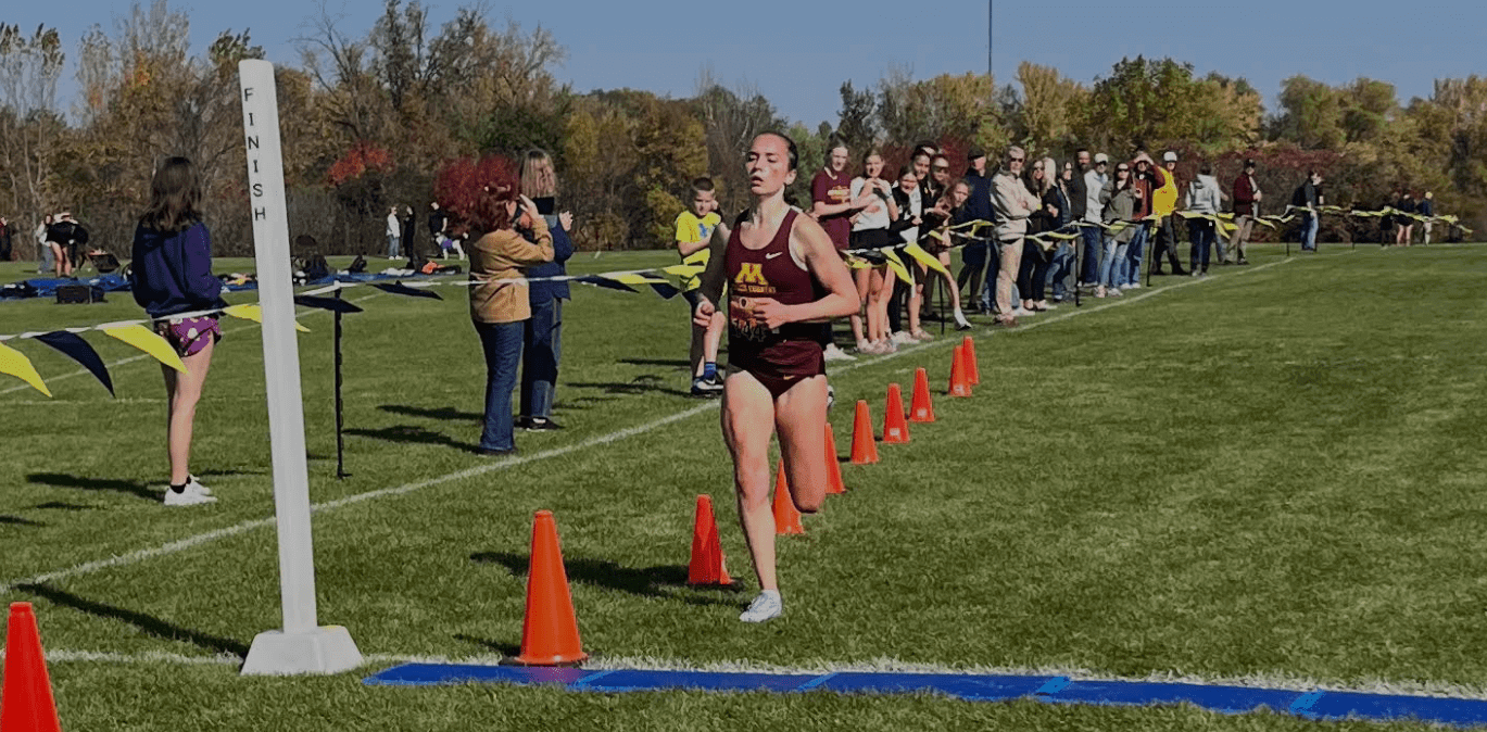 Runner approaching finish line in cross-country race.